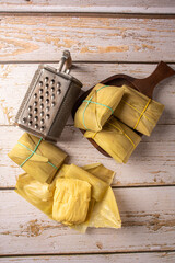 Pamonha, corn-based Brazilian food, arranged on a rustic wooden table, top view.