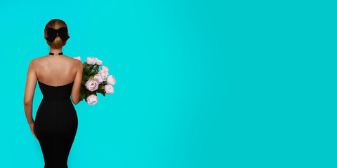 A girl in a tight black dress standing with her back and holding a bouquet of peonies on a tiffany blue background. - obrazy, fototapety, plakaty