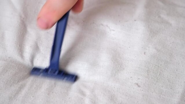 A man removes fabric pills using a disposable shaving machine. A razor for removing pellets.