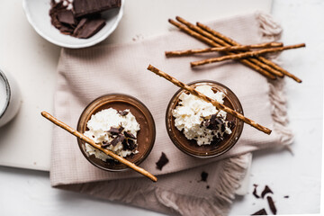 Fototapeta premium chocolate cake with coffee chocolate mousse cream in a glass cup on a white background with whipped cream and salty sticks snack snack sweet dessert