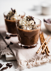 chocolate cake with coffee 
chocolate mousse cream in a glass cup on a white background with whipped cream and salty sticks snack snack sweet dessert