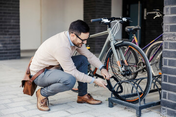 Obraz na płótnie Canvas A casual businessman locks up his bicycle on the street.