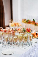 Stylish champagne glasses and food appetizers on table at wedding reception