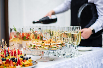 Stylish champagne glasses and food appetizers on table at wedding reception