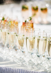 Stylish champagne glasses and food appetizers on table at wedding reception