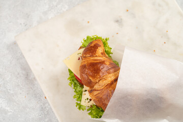 lye croissant sandwich with iberian ham, tomato slices, lettuce and cheese in a breakfast white...