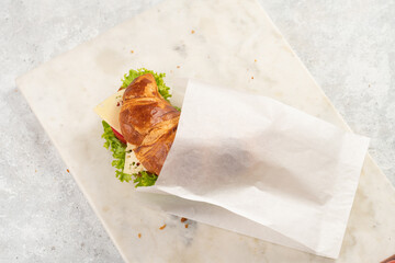 lye croissant sandwich with iberian ham, tomato slices, lettuce and cheese in a breakfast white...