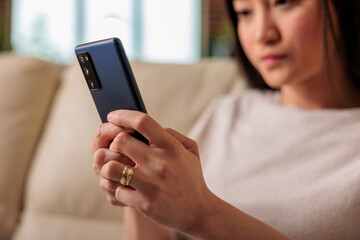 Casual authentic looking happy asian woman using smartphone at home, web internet technology smartphone user mobile message social media communication digital device