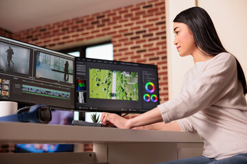 Asian videographer working on editing video and audio footage with professional software to create...