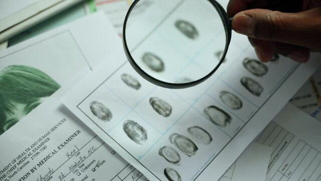 Detective investigating fingerprints with magnifying glass. Professional making dactyloscopic expertise of fingerprints. High quality 4k footage