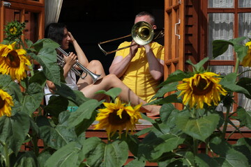 A guy with a girl play a musical instrument trumpet trombone in the window of a country house with...