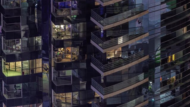 Night view of many glowing windows in apartment residential tower aerial timelapse. High rise skyscraper with lights in rooms