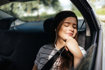 Young woman relaxing in the back seat of the car on a sunny day