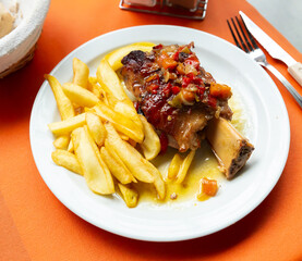 Appetizing baked pork knuckle (Codillo) with French fries on plate