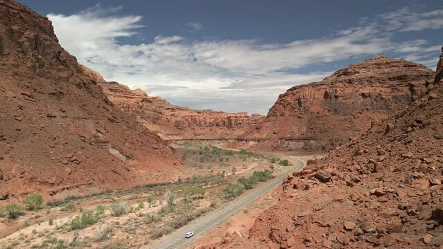 Aerial view of car driving on the highway through a Utah desert canyon in red rock country.