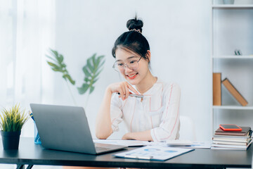 Portraits of beautiful smiling Asian women relax using laptop computer technology while sitting on their desks and using their creativity to work