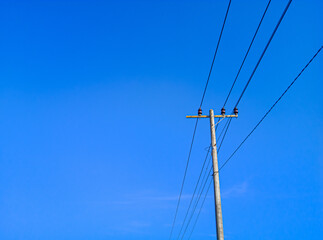 Fototapeta premium electric pole in a minimalist composition on a bright blue sky with empty space to enter text