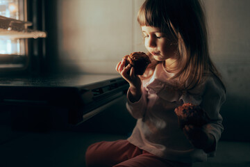 Adorable Little Toddler Girl Having a Freshly Baked Cupcake. Little child eating muffing on the...