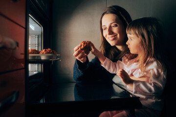 
Happy Mom and Child Sharing Homemade Cupcakes. Mother and daughter having a treat after baking in the kitchen