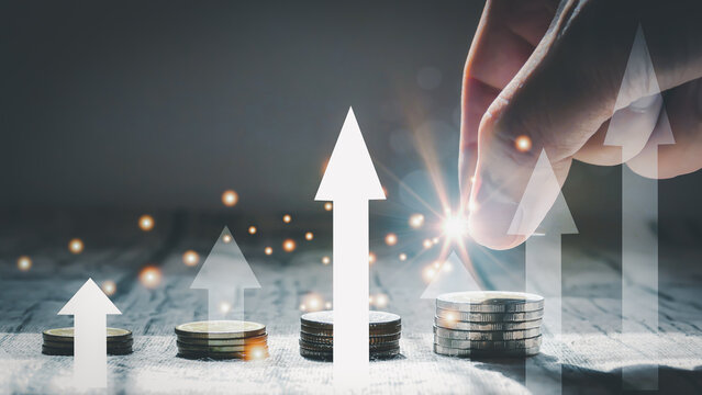 Man hand stacked coins with money saving concept and profit graph business finance in a piggy bank with money boxes for future funds of tourism, home, and retirement on a blurred background.