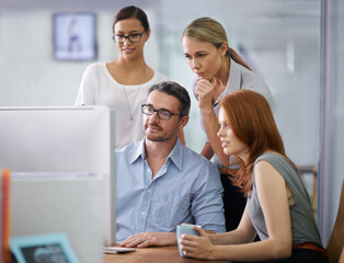 Professional business people developing strategy, ideas and planning in front of a computer in the office space. Team of corporate workers analyzing data and discussing a business plan together