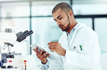 Serious male scientist working on a tablet reviewing an online phd publication in a lab. Laboratory worker updating health data for a science journal. Medical professional document clinical trial - obrazy, fototapety, plakaty
