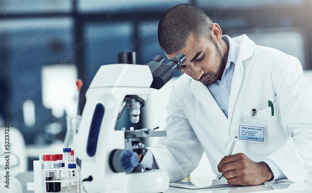 Poster focused male lab technician using digital tablet working on medical development and innovation proje