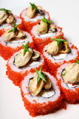 Elite sushi on a white background in red tobiko caviar with mussels on top. Food