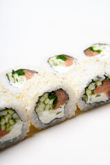 Sushi on a white background in sesame. Philadelphia with cucumber roll. Food.