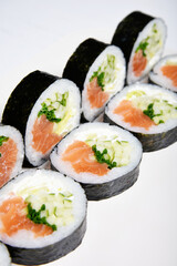 Sushi on a white background in sesame seeds with avocado and nigiri. Futomaki with salmon and cucumber. Food.