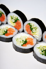 Sushi on a white background in sesame seeds with avocado and nigiri. Futomaki with salmon and cucumber. Food.