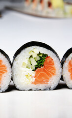 Sushi on a white background in sesame seeds with avocado and nigiri. Futomaki with salmon and cucumber. Food.
