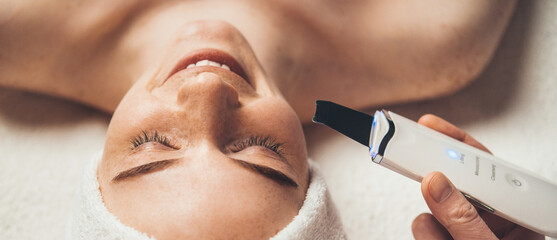 Close-up portrait of smiling woman receiving ultrasound cavitation facial peeling. Skin treatment....