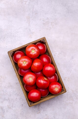 Large raw red tomatoes in a wooden box