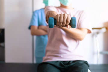 Fototapeta na wymiar Physiotherapist women training with men patient using dumbbells in clinic,Physical therapy concept