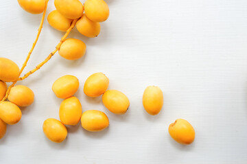 Fresh yellow dates on a white wooden floor, top view.