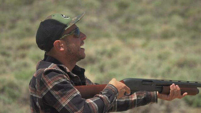 Caucasian man skeet shooting with a shotgun with heavy recoil at firing range