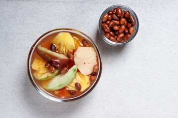 Asinan Buah Bogor or Rujak Buah, fruit pickle made from sliced fresh tropical fruits on sweet, sour and spicy red soup. Topped with fried peanuts.