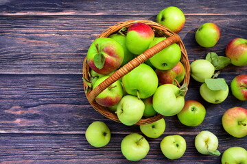 red green apples in wicker basket and dark wooden boards with copy space and empty place. Top view, flat lay
