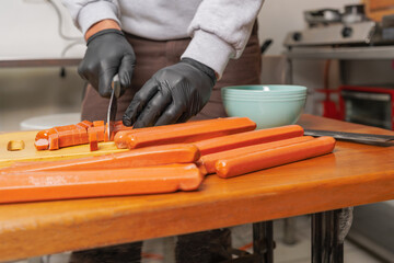 Cropped photo of a man chopping frankfurter in a kitchen