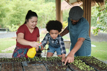 African American farmer family teaches their son to plant seedlings in vegetable gardening nursery plots for nature ecology learning, organic gardener hobby, happy together with childhood agriculture. - Powered by Adobe