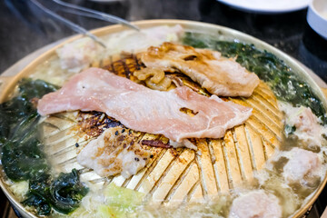 Thai style barbecue or Mookata, raw meat with spicy sauce grilled on the stove.