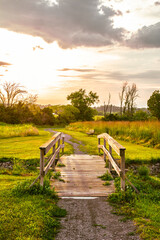 The pathway with the wooden bridge illuminated by the sunset sky
