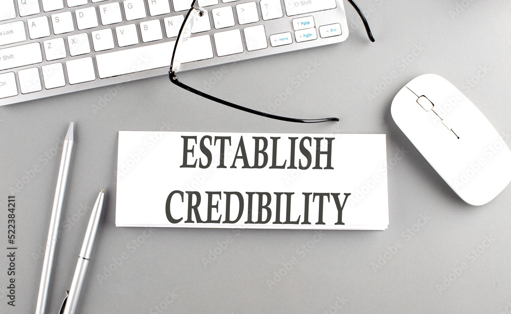 Poster establish credibility text on paper with keyboard on grey background