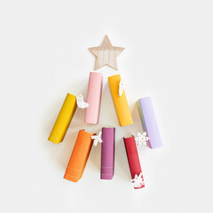 Christmas tree of colors paper books, New Year fir shape with wooden toys, colorful covers of books as holiday Christmas tree. Studying, education concept. Top view greeting card