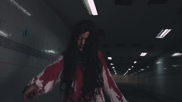 Bloody halloween makeup. Asian woman zombie with blood she death and scary walking come to camera at dark night, Horror bloodthirsty ghost girl walk reach arm out, Happy halloween day concept