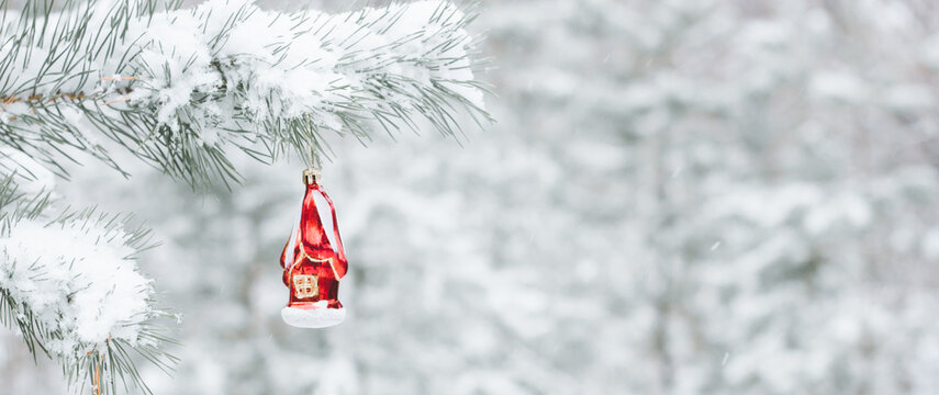 Background of winter Christmas holiday - toys on a branch of a Christmas tree and a blurred snowy background in the background, photo banner with copy space.