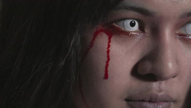 Bloody halloween makeup. Close up of horror bloodthirsty ghost female with fade drop out from eyes, Asian woman with blood eye she death and scary with blood tear on face, Happy halloween day concept