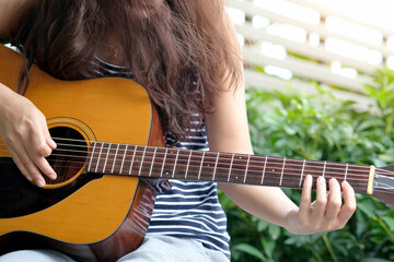 woman playing her acoustic guitar stringed instrument practicing catching and learn the musical...
