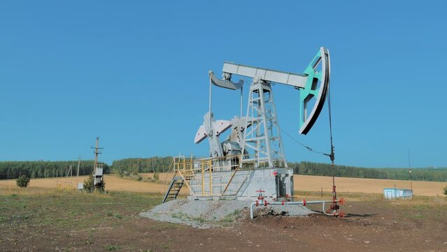 Pumping rig extracting oil from an oil well in vast oil field. Oil Industry Equipment.